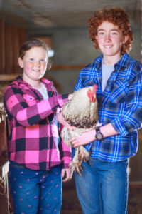 Boy and girl holding a chicken