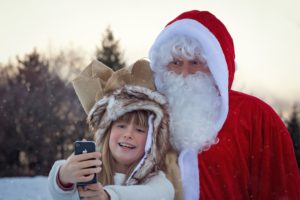 holiday season: santa claus taking a selfie with a young boy outside