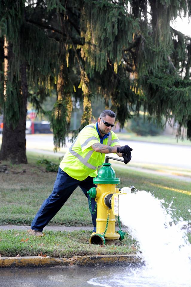 Flushing Program: a man in a reflective vest opening a yellow and green hydrant