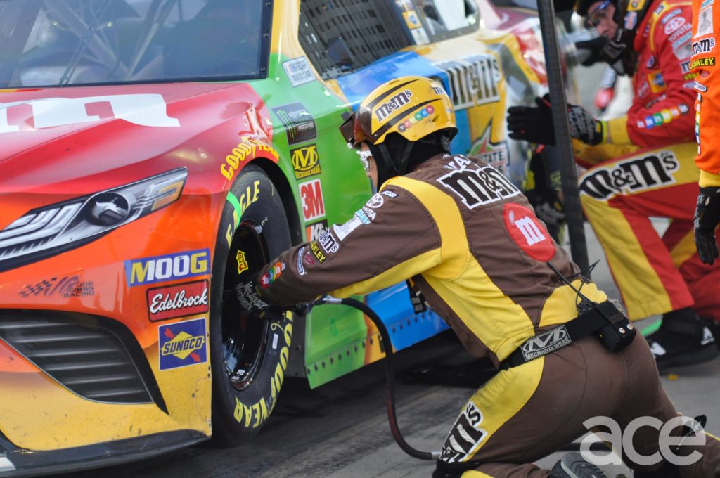 Pit crew member changing the left front tire of Kyle Busch's No. 18 M&Ms Car.