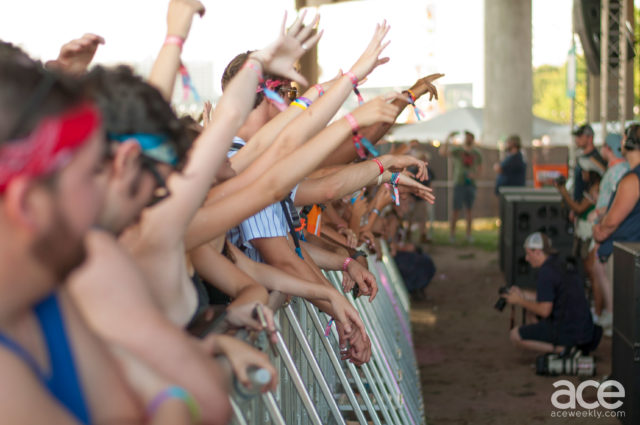 side view of crowd with arms in air cheering at music festival