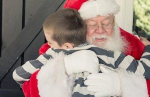 holiday season: santa claus hugging a child in a stripped sweater