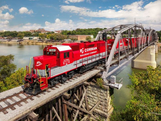 red rj corman train going over a bridge