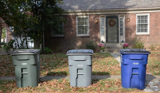 3 trash bins in front of a house