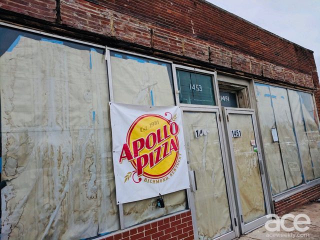an outdoor shot of a buliding with brown paper in windows and an apollo's pizza sign
