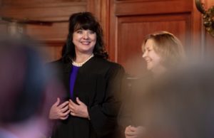 supreme court: a woman in a blue dress with a black judges robe smiling
