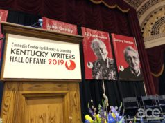 a podium with the kentucky writers hall of a fame sign and two banners with ed and gurney's faces and names on it
