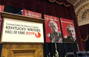 a podium with the kentucky writers hall of a fame sign and two banners with ed and gurney's faces and names on it