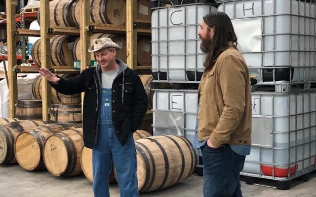 Moonshiners: two men standing in front of barrels talking