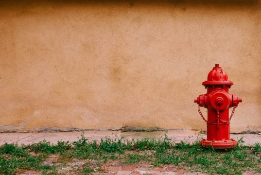 red hydrant against a beige wall