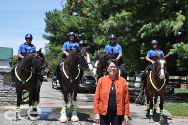 police officers on horses with a woman in an orange jacket standing in front of them