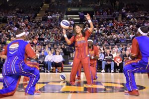 harlem globetrotters: girl in red uniform spinning in a ball while guys in another color uniform watch