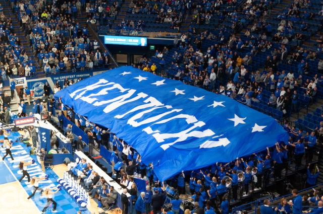 basketball: stand full of people pulling a big blue banner that says kentcuky with 8 stars