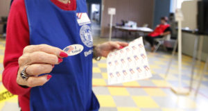 primary election Community: Volunteer handing out I Voted stickers after filling out a election ballot at a district voting station